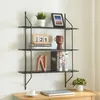 A black metal wall shelf with decorative items on it, placed above a wooden desk. Produktbild-Vorschau