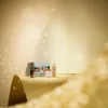A collection of beauty products displayed on a glittering gold surface with a soft, glowing background and sparkling effects. Produktbild-Vorschau