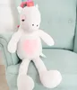 A white plush unicorn toy with a pink heart on its chest sits on a light blue armchair. Produktbild-Vorschau