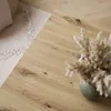 A close-up of a wooden coffee table with a vase of dried flowers. Produktbild-Vorschau