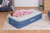 A woman is sleeping on an inflatable mattress in a room. Produktbild-Vorschau