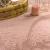 A close-up view of a fluffy pink rug with a yellow basket and a candle on it. Voir les images du produit