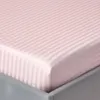 A close-up view of a pink striped fitted sheet on a bed. Náhled obrázku produktu