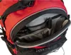 A close-up view of the open front pocket of a red and black backpack, showing internal compartments and items like a pen and earbuds. Produktbild-Vorschau