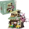 A detailed model of a Japanese-style building with a cherry blossom tree, next to its product packaging. Produktbild-Vorschau