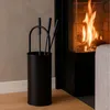 A fireplace set with tools in a holder next to a burning fireplace. Produktbild-Vorschau
