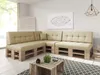A sectional sofa made of wooden pallets with beige cushions in a bright, modern living room. Produktbild-Vorschau