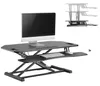 A height-adjustable standing desk converter with a monitor, keyboard, and mouse on it, shown against a white background. A smaller inset image shows the desk converter at different height levels. Anteprima dell’immagine prodotto