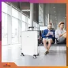 Two men are sitting in an airport waiting area with a large white suitcase in the foreground. Produktbild-Vorschau