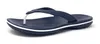 A single navy blue Crocs flip-flop with a white stripe around the sole, shown from a side angle on a white background. Produktbild-Vorschau