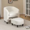 A white armchair and ottoman are placed on a rug in a room with a cabinet in the background. Produktbild-Vorschau