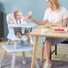 A mother is feeding her baby in a high chair at a dining table. Podgląd zdjęcia produktu