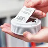 Hands holding a smoke detector and an instruction label. Produktbild-Vorschau