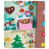 A festive scene depicting a gingerbread house and Christmas tree, with a character baking a cake in an oven. Voir les images du produit