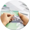 Hands are shown applying a clear protective film to a stack of papers or photos. Produktbild-Vorschau