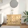 A wooden sideboard with drawers and doors is shown in a room with a sofa and a plant. Podgląd zdjęcia produktu