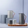 Two pitchers and two cups arranged on a tray, with decorative blocks in the background. Voir les images du produit