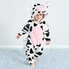 A baby wearing a cow costume stands on a blue carpet against a white background. Produktbild-Vorschau
