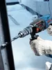 A person wearing a work glove is using a Bosch hammer drill to drill into a metal beam. Náhled obrázku produktu