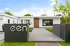 A modern white house with a concrete pathway leading to the entrance, flanked by dark gray planters and a mailbox. The word 'een' is prominently displayed in silver letters on one of the planters. Náhled obrázku produktu