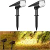 Two black solar-powered garden spotlights are shown against a white background. Below them, a separate image shows two similar spotlights illuminating a garden at night. Anteprima dell’immagine prodotto