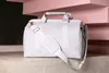 A light gray duffel bag with white straps and copper accents is placed on a tiled surface in front of pink geometric shapes. Produktbild-Vorschau