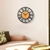 A wall clock with Roman numerals is mounted on a white wall above a pink sofa with decorative pillows. Produktbild-Vorschau