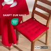A red chair cushion on a wooden chair next to a red tablecloth. Anteprima dell’immagine prodotto