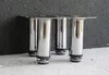 Four silver furniture legs with black rubber bases are shown against a dark textured wall and a light grey surface. Podgląd zdjęcia produktu