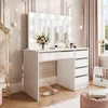 A white vanity table with a lighted mirror, drawers, and makeup accessories is shown in a well-lit room with soft curtains and a window. Voir les images du produit