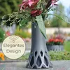 A vase with flowers placed outdoors, possibly in a garden or cemetery setting. Produktbild-Vorschau
