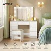A white dressing table with a lighted mirror and a stool, set in a bedroom with a bed and wall sconces. Produktbild-Vorschau