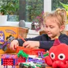A young girl is playing with building blocks on a table. Produktbild-Vorschau