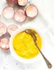 A bowl of yellow puree with a spoon, surrounded by empty passion fruit shells. Podgląd zdjęcia produktu
