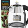 A close-up marketing image of a glass and stainless steel electric kettle with a visible tea infuser mechanism. The left side of the image displays various types of loose leaf tea in small bowls. Produktbild-Vorschau