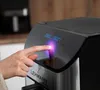 A hand is shown pressing a button on the control panel of a black air fryer. Náhled obrázku produktu