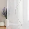 A close-up of a sheer white curtain with a decorative wavy pattern and a bouquet of lavender in a vase. Produktbild-Vorschau
