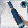 A hand holding a closed blue automatic folding umbrella. Náhled obrázku produktu