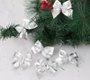 Silver bows are placed on a Christmas tree branch with red berries. Náhľad obrázku produktu