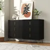 A black dresser with gold handles and legs is shown in a well-lit room, with a piece of abstract art on top and a plant in the background. Podgląd zdjęcia produktu