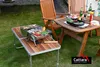 A barbecue setup in a garden with a grill on a table and chairs nearby. Náhled obrázku produktu