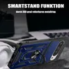 A close-up of a blue and black phone case with a ring stand, placed on a textured surface with a blurred background of a laptop and headphones. Produktbild-Vorschau