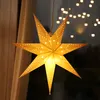 A lit paper star decoration hangs in front of a window with blurred lights in the background. Produktbild-Vorschau