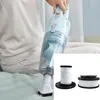 A person is using a handheld vacuum cleaner on a bed, with a close-up of replacement filters in the foreground. Produktbild-Vorschau