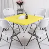 A square yellow table with four white chairs around it, set up in a room. Produktbild-Vorschau