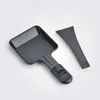 A black raclette pan and scraper are laid out on a light gray and white background. Voir les images du produit