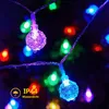 Close-up of colorful LED string lights with water droplets on them, set against a dark, blurred background. Produktbild-Vorschau