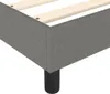 Close-up view of a gray fabric bed frame with wooden slats and black legs. Voir les images du produit