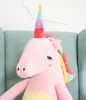 A close-up shot of a large, pink plush unicorn toy sitting on a light blue armchair. Produktbild-Vorschau