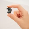 A hand holds a small black earphone. Produktbild-Vorschau
